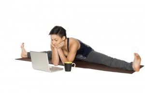 Woman in a yoga stretch position in front of her laptop