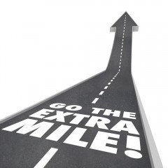 Street turning into an arrow with white paint on it saying "Go the Extra Mile"