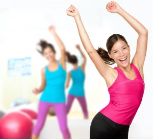 Energetic, happy fitness women dancing in a group class setting.