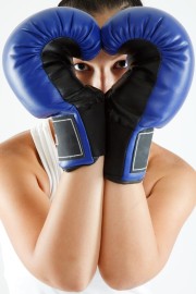 young woman in gym clothes, wearing blue boxing gloves shaped as a heart